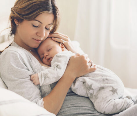 Loving mom carying of her newborn baby at home. Bright portrait Loving mom carying of her newborn baby at home. Bright portrait of happy mum holding sleeping infant child on hands. Mother hugging her little 2 months old son.